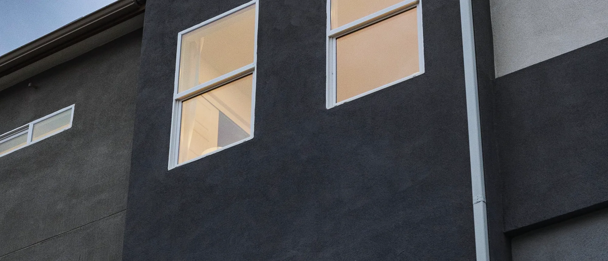 Exterior glazing on a dark rendered two-storey home