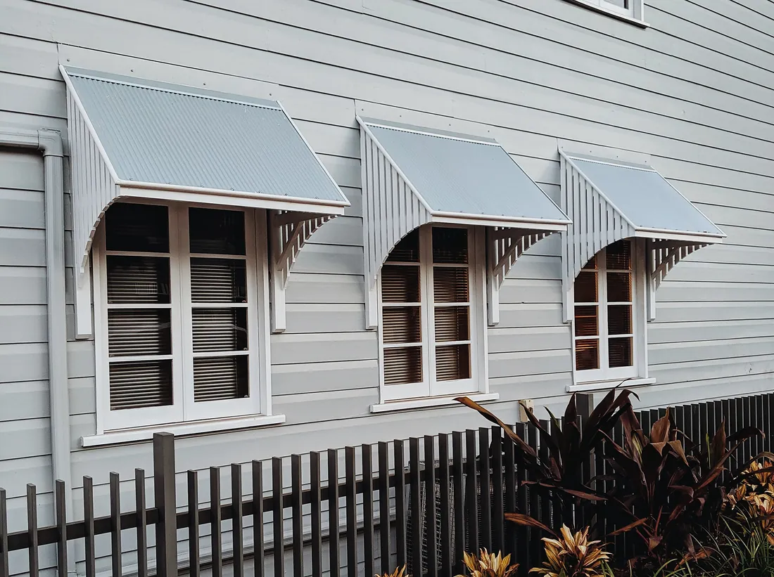 Weatherboard house exterior with window awnings