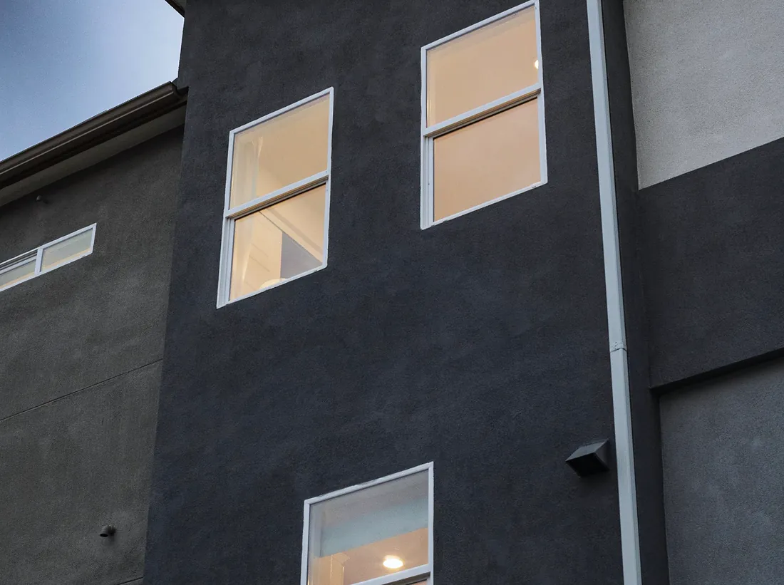 Tall white-framed windows on a dark rendered contemporary home